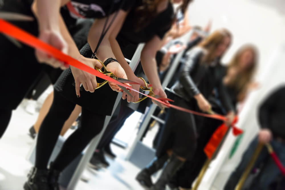 a group of people cutting red ribbon