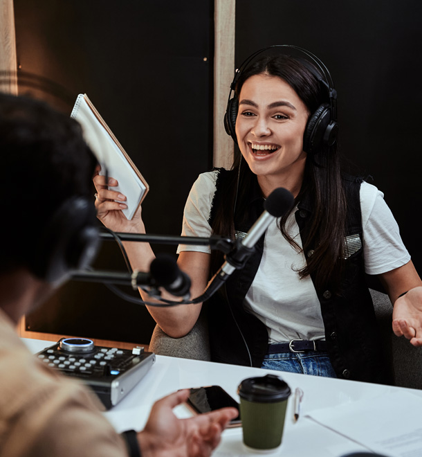 a woman wearing headphones and talking to a man in a microphone