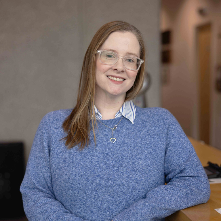 a woman wearing glasses and a blue sweater