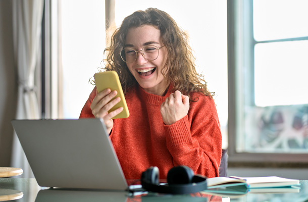 a woman sitting at a desk with a laptop and a phone