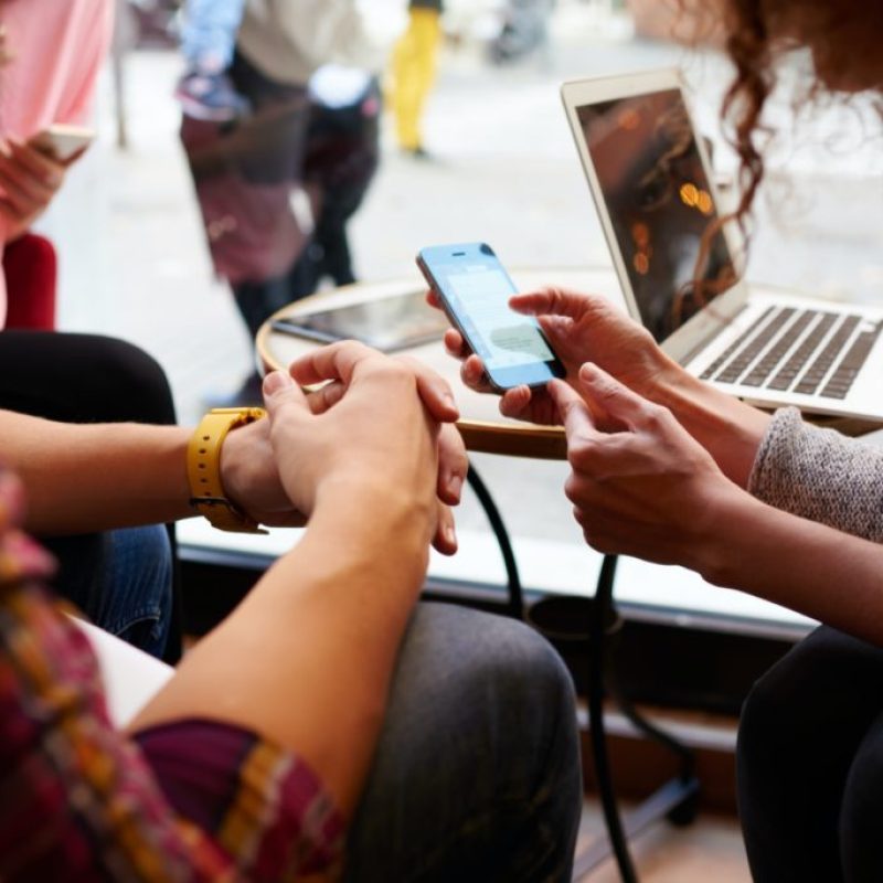 socialmediaservice a group of people sitting at a table using a phone